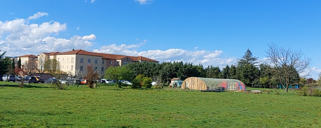 Photo du parc de la maison de retraite de Livron-sur-Drôme. En arrière plan l'établissement Cauzid et la serre pédagogique de Val de Terre, l'activité de paysannerie de val d'Emploi.