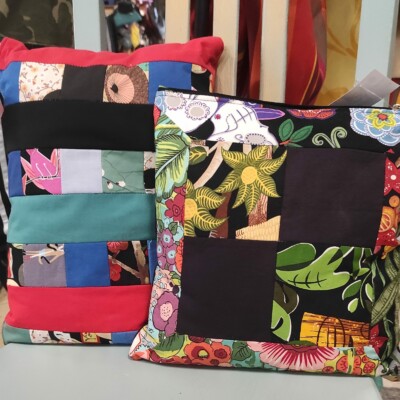 Photo de deux coussins cousus en patchwork par Les Mains d'Or, l'atelier de créations couture et upcycling de Val d'Emploi à Livron-sur-Drôme.