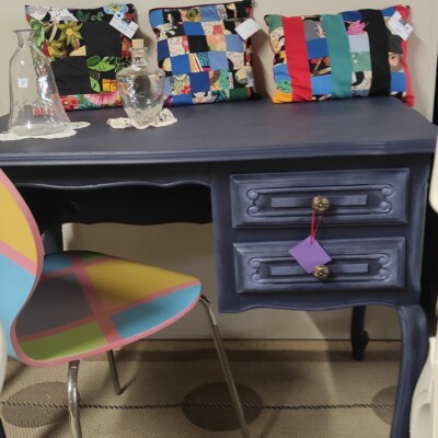 Une photo d'un bureau customisé dans un style vintage et peint en bleu accompagné d'une chaise relookée elle aussi et de coussins confectionnés par Les Mains d'Or.