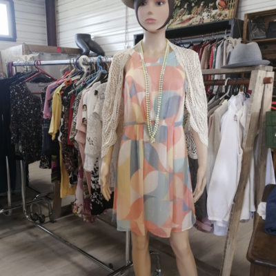 Photo du rayon vêtements de l'Astucerie avec un manequin protant une robe d'été en avant-plan.